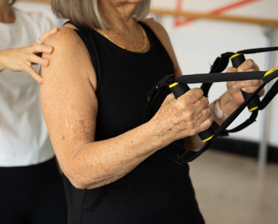 An older woman being guided by a physiotherapist in a clinical pilates class