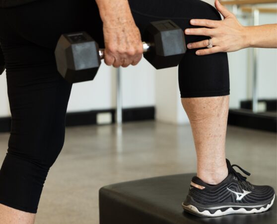 Physiotherapist guides a participant in clinical pilates class