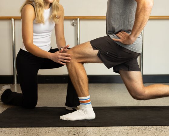 Physiotherapist guides a participant in clinical pilates class
