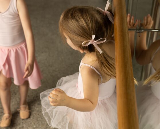 Little ballerina with pigtails talking to her friend